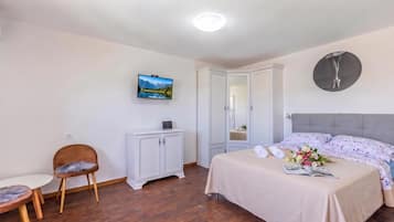Un dormitorio con una cama, una silla, un armario, un televisor y un espejo.