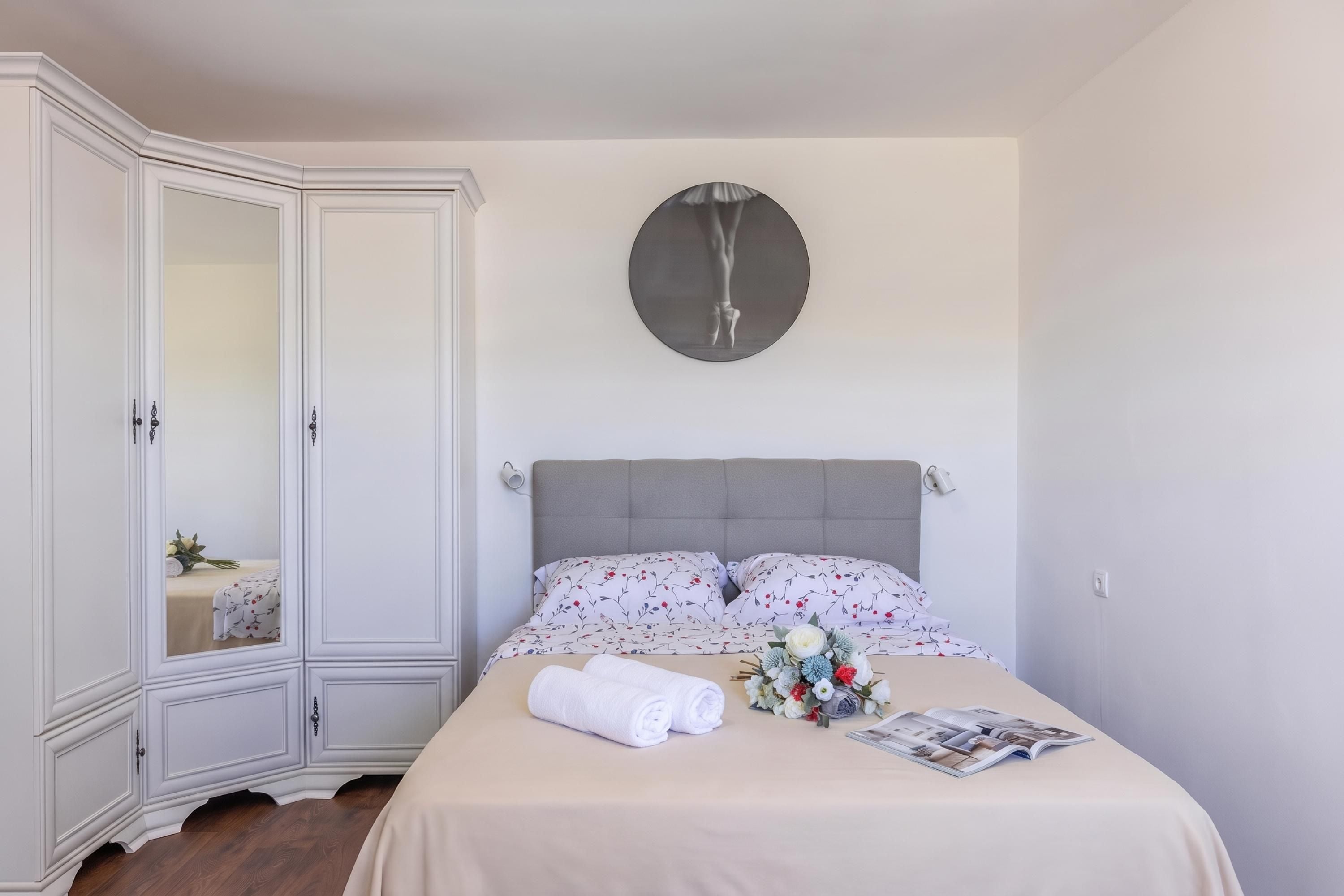 Une chambre à coucher avec un lit, une armoire, un miroir rond et une horloge au mur.