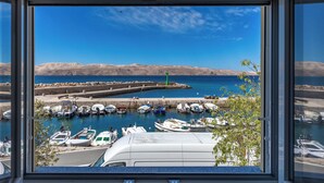 A marina with boats docked, a clear blue sky, and distant mountains. - 1BR Seafront Apartment Sanja Karlobag (Karlobag)