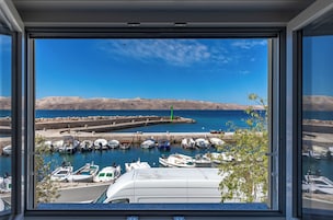 Un puerto deportivo con barcos amarrados, un cielo azul despejado y montañas a lo lejos.