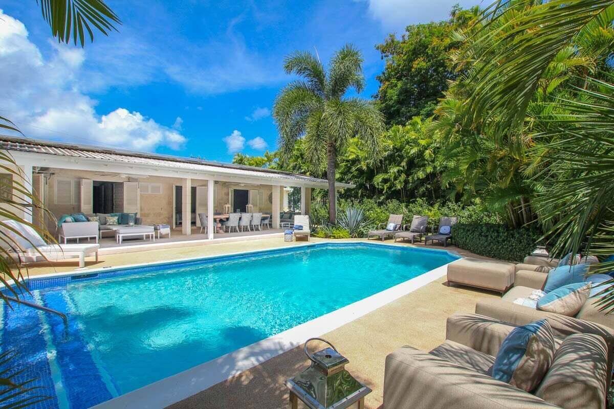 Piscina com espreguiçadeiras e área de estar coberta.