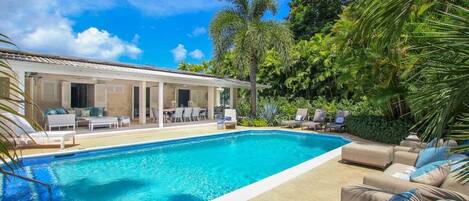 A swimming pool with lounge chairs and a covered patio area.