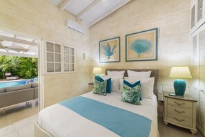 A bedroom with a bed, two bedside tables, a nightstand, a window with a view of a pool, and two framed artworks on the wall. - Palm Grove by Bluescape (Mullins)