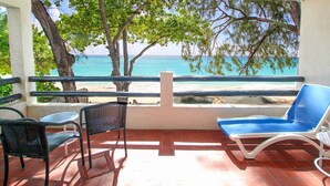 A balcony with a view of the beach, a blue lounge chair, and two wicker chairs. - 3 Sea Star by BSL Rentals (Worthing)
