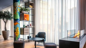 Un salon moderne avec une table ronde, deux poufs, une bibliothèque et une cheminée.