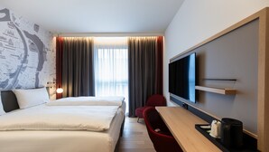 Une chambre d’hôtel avec un grand lit, un bureau avec une chaise, un téléviseur à écran plat et une carte accrochée au mur.