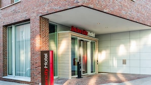 L'entrée de l'hôtel Intercity se distingue par sa façade en briques, ses grandes portes vitrées et une vue dégagée sur l'intérieur.
