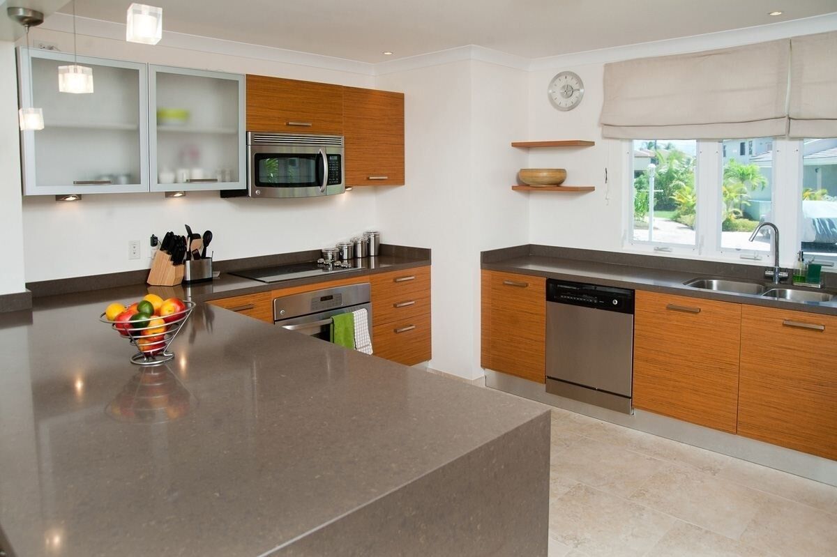 A modern kitchen with a central island, stainless steel appliances, wooden cabinets, and a window with a view.