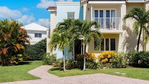 A two-story house with a balcony, surrounded by palm trees and well-maintained lawn. - Palisades 6a 3 Bedroom Townhouse (Oistins)