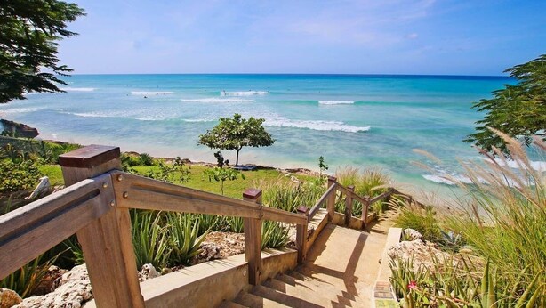 A wooden staircase leading to a beach with clear turquoise water and a view of the ocean. - Palisades 6a 3 Bedroom Townhouse (Oistins)