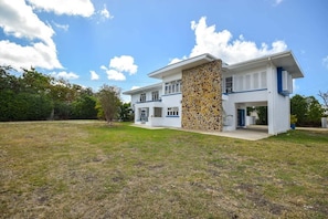 A modern two-story house with a stone facade, a flat roof, and a large front lawn.