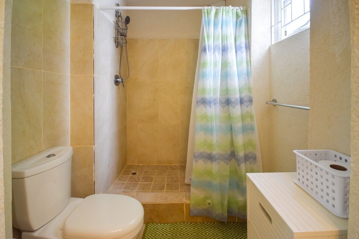 A small bathroom with a shower, toilet, and a sink with a basket.