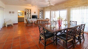 A spacious living area with a wooden dining table, chairs, and a television. - Church Point Cottage 3 Bedroom Home by Bluescape (Holetown)