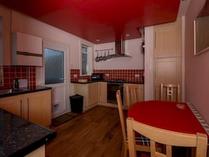 A compact kitchen with wooden cabinets, a red dining table, and a microwave. - Private Entrance GF 2 bed flat near Renfrew Centre - Pass the Keys (Renfrew)