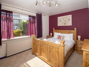 A bedroom with a wooden bed, a radiator, a window with curtains, and a wall-mounted artwork. - Private Entrance GF 2 bed flat near Renfrew Centre - Pass the Keys (Renfrew)