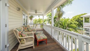 Eine überdachte Veranda mit Korbmöbeln und Blick auf die grüne Umgebung.