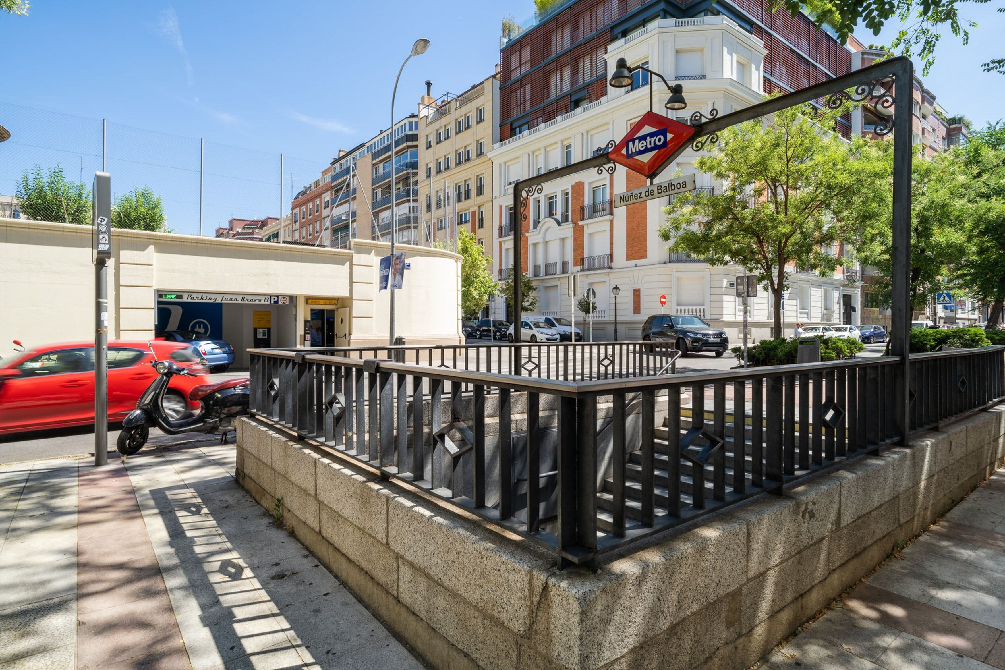 A street view with a Metro sign, parked cars, and buildings in the background.