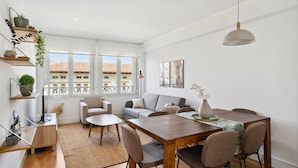 A modern living room with a dining area, large windows, and a view of buildings. - Limehome Madrid Calle de Nuñez de Balboa (Madrid)