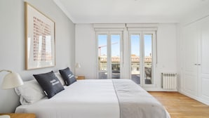 A bedroom with a large bed, a framed artwork, a nightstand, a lamp, and a view of the outside through a sliding glass door. - Limehome Madrid Calle de Nuñez de Balboa (Madrid)
