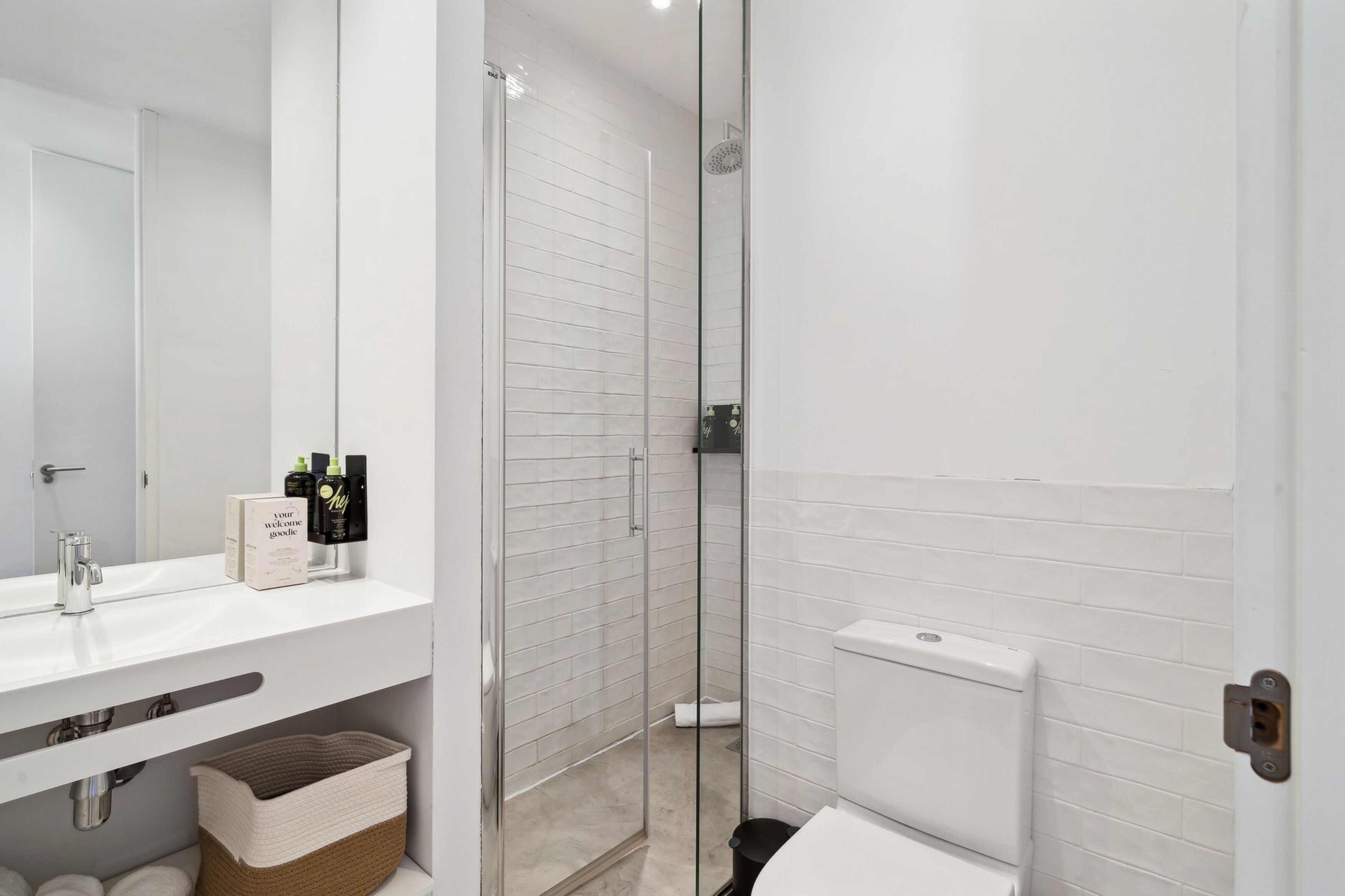 A modern bathroom with a glass-enclosed shower, a white sink, and a toilet.