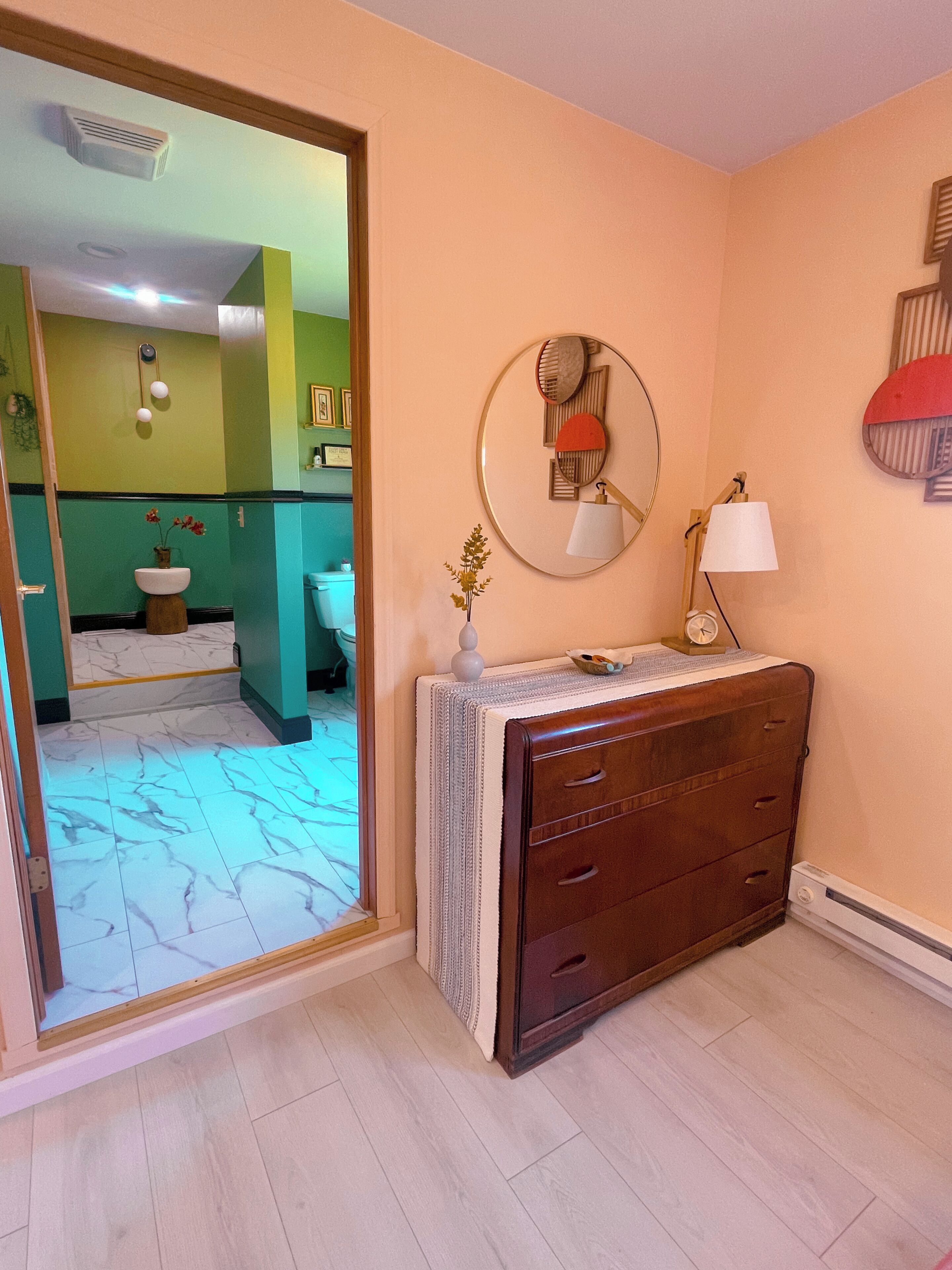 A bathroom with a mirror, a sink, a toilet, and a vanity with drawers.