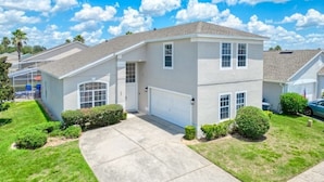 A two-story residential house with a garage, a front lawn, and a clear blue sky.