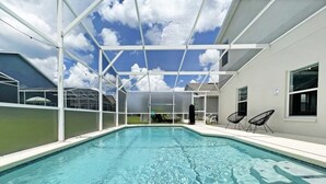 A swimming pool with a glass ceiling, surrounded by white walls and a few chairs.