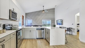 A modern kitchen with white cabinetry, stainless steel appliances, and a large island.