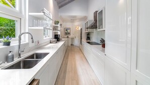 A modern kitchen with white cabinetry, stainless steel appliances, and a wooden floor.