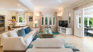 A spacious living room with a sofa, coffee table, TV, and a ceiling fan.