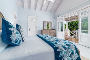 A bedroom with a bed, a dresser, a mirror, and a door leading to an outdoor area. - Royal Westmoreland - Lime Tree House 3 Bedroom Villa (Westmoreland)