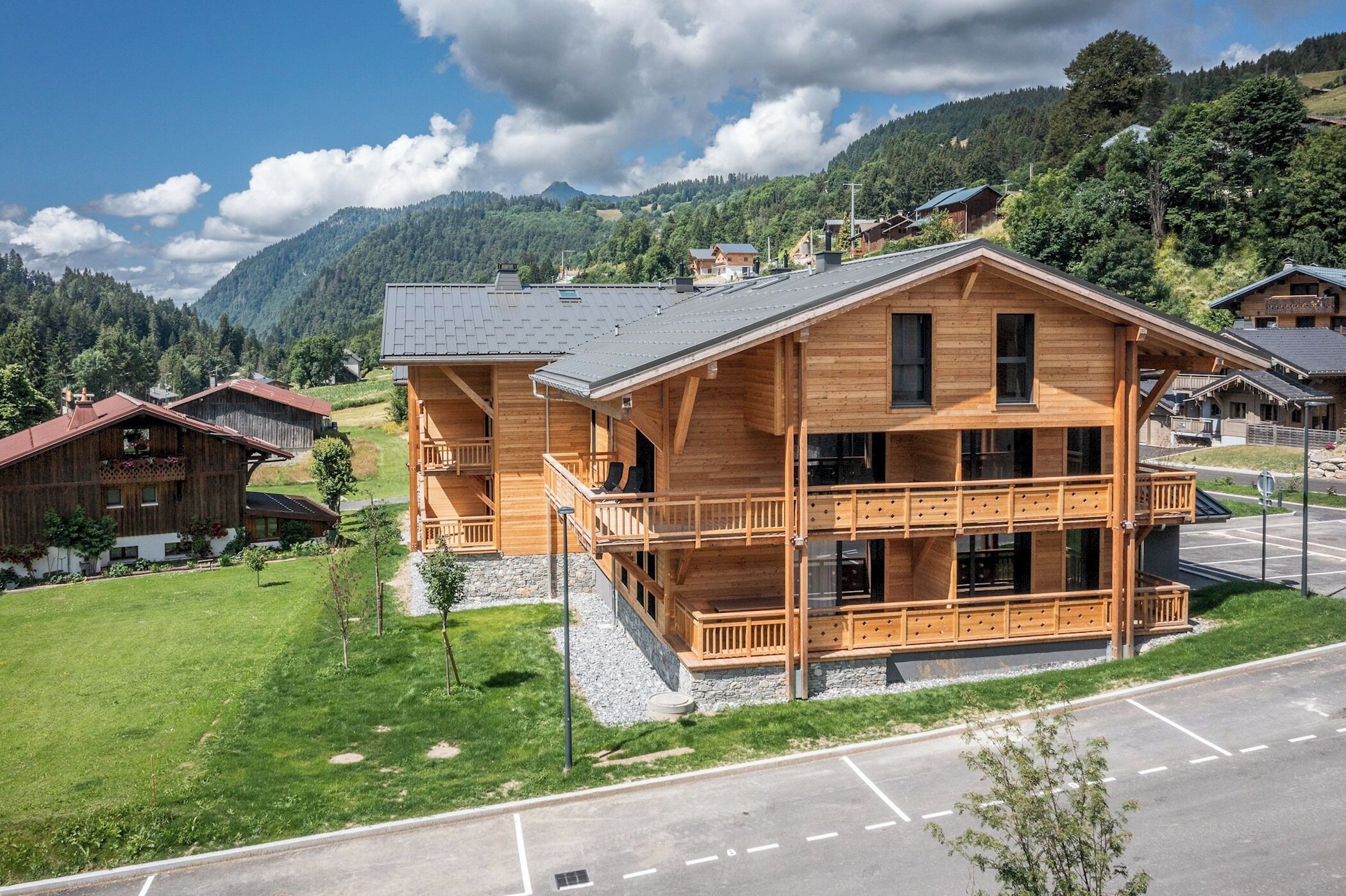 Eine Holzhütte mit Balkon, gelegen in einer Bergregion mit Parkplatz vor der Tür.