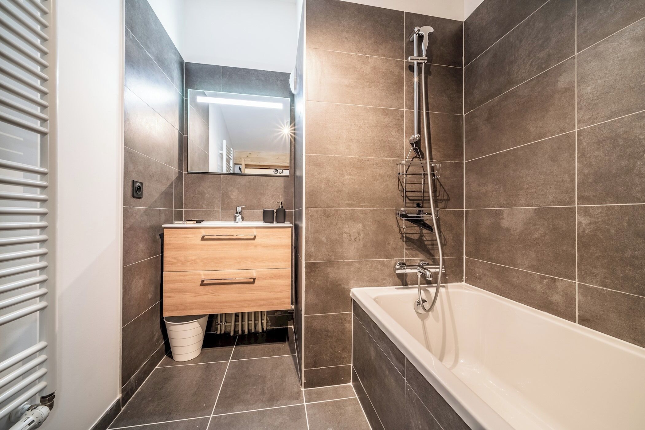 Ein modernes Badezimmer mit Badewanne, Dusche und Waschtisch inklusive Spiegel.