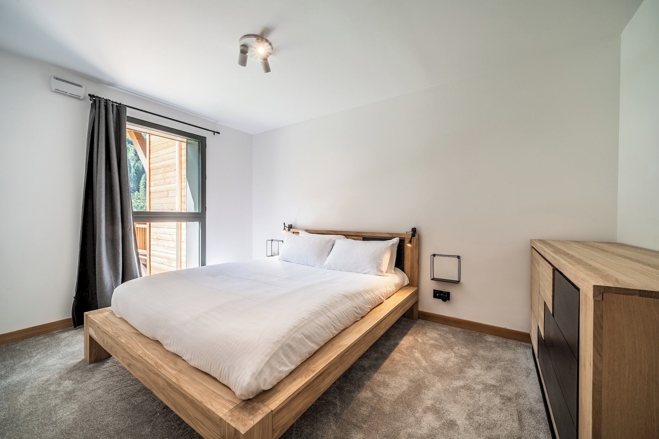 A bedroom with a wooden bed, a window with curtains, a ceiling fan, and a built-in TV cabinet.