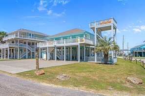 Un hotel frente a la playa con varios balcones, un atrio central y una estructura elevada distintiva.