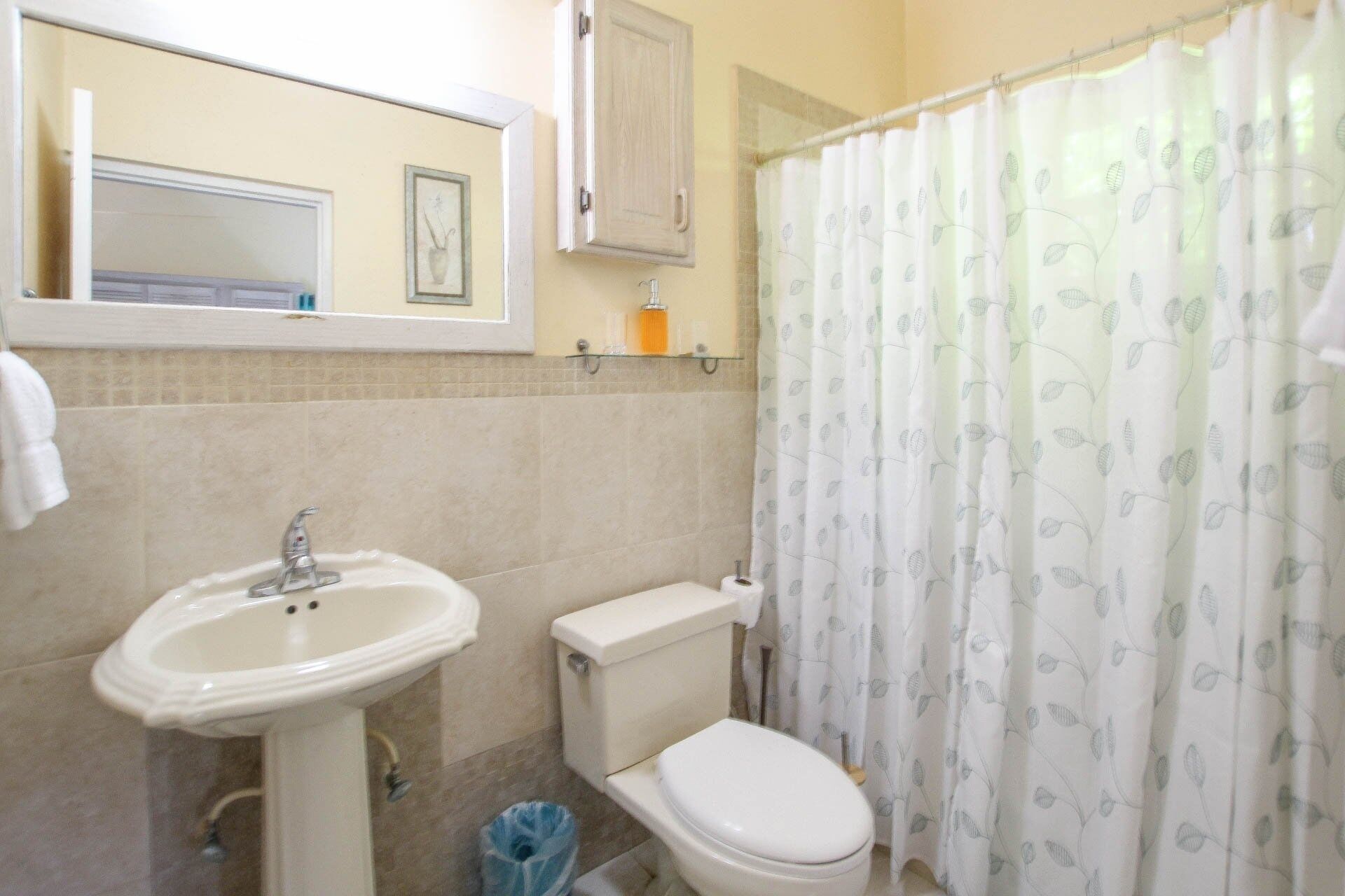 Un baño con lavamanos, inodoro y cortina de ducha.