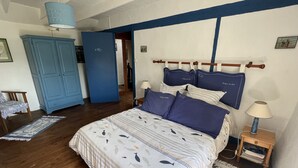 Une chambre à coucher comprenant un lit, des tables de chevet, une armoire et une porte donnant sur une autre pièce.