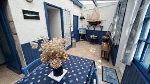 Une pièce avec une table dressée pour le repas, un banc, une plante décorative et une maquette de voilier.