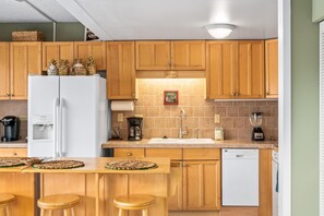Una cocina con armarios de madera, un refrigerador blanco, una cafetera y un lavavajillas.