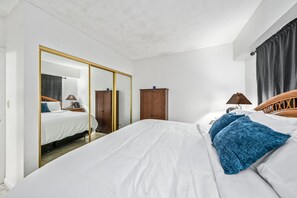 Un dormitorio con una cama grande, un armario, un espejo y una ventana con cortinas.