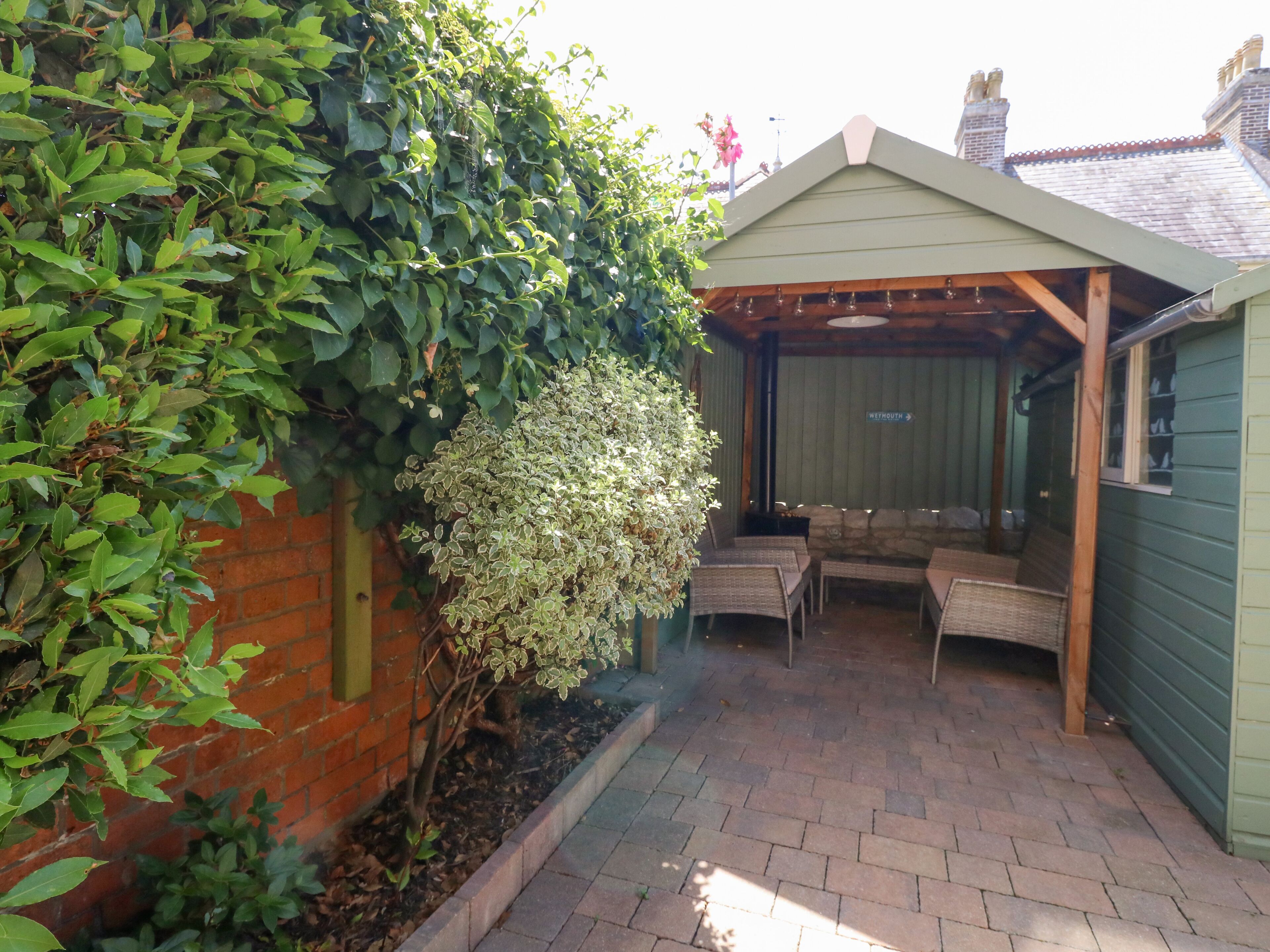 A covered patio area with a brick floor and a wooden pergola.
