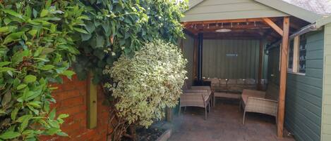 A covered patio area with a brick floor and a wooden pergola.