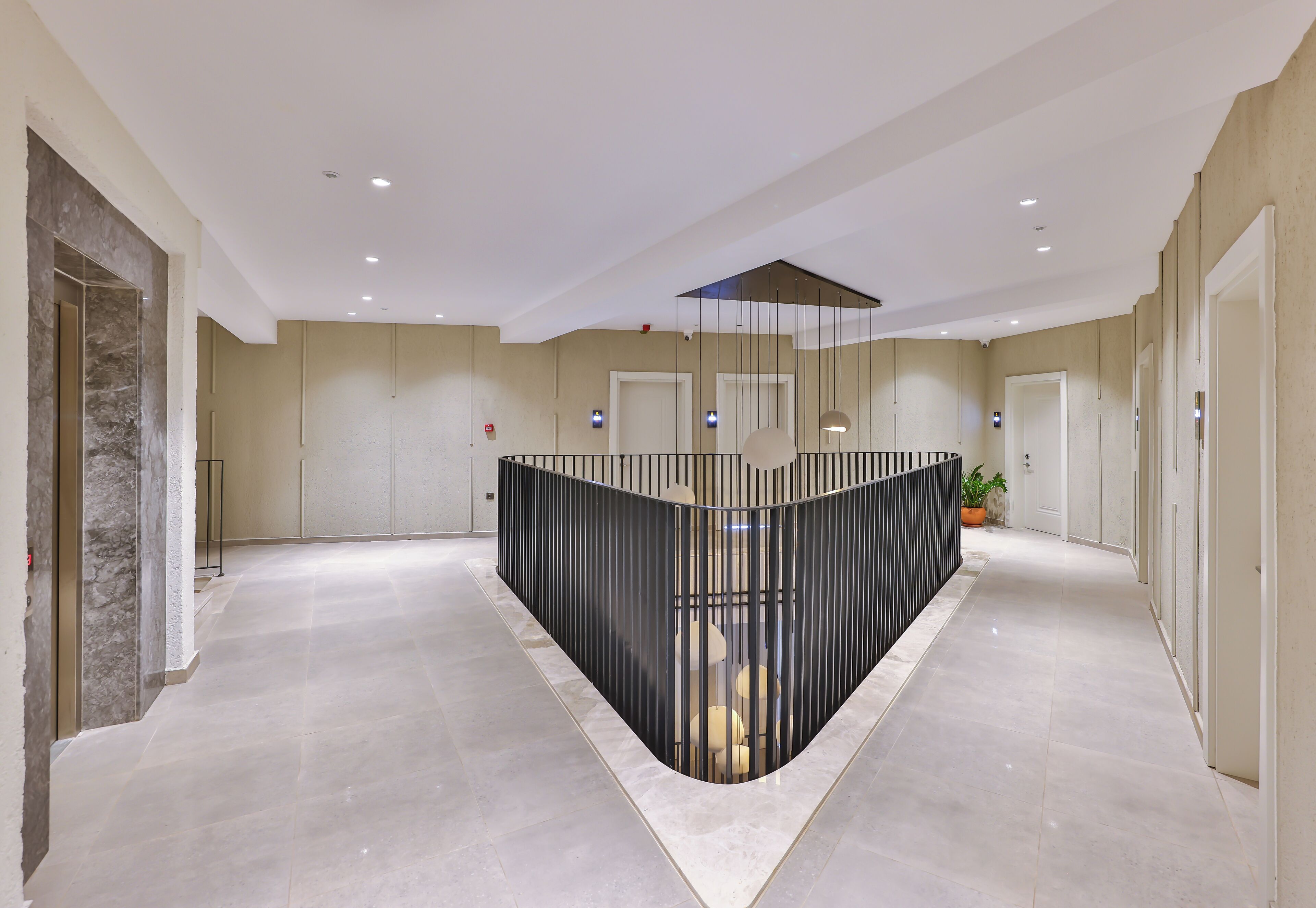A modern hotel lobby with a central reception desk, recessed lighting, and a marble floor.