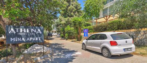 A paved driveway leading to a building with a sign for 'ATHENA HOTEL - KAS MİNA APART.'