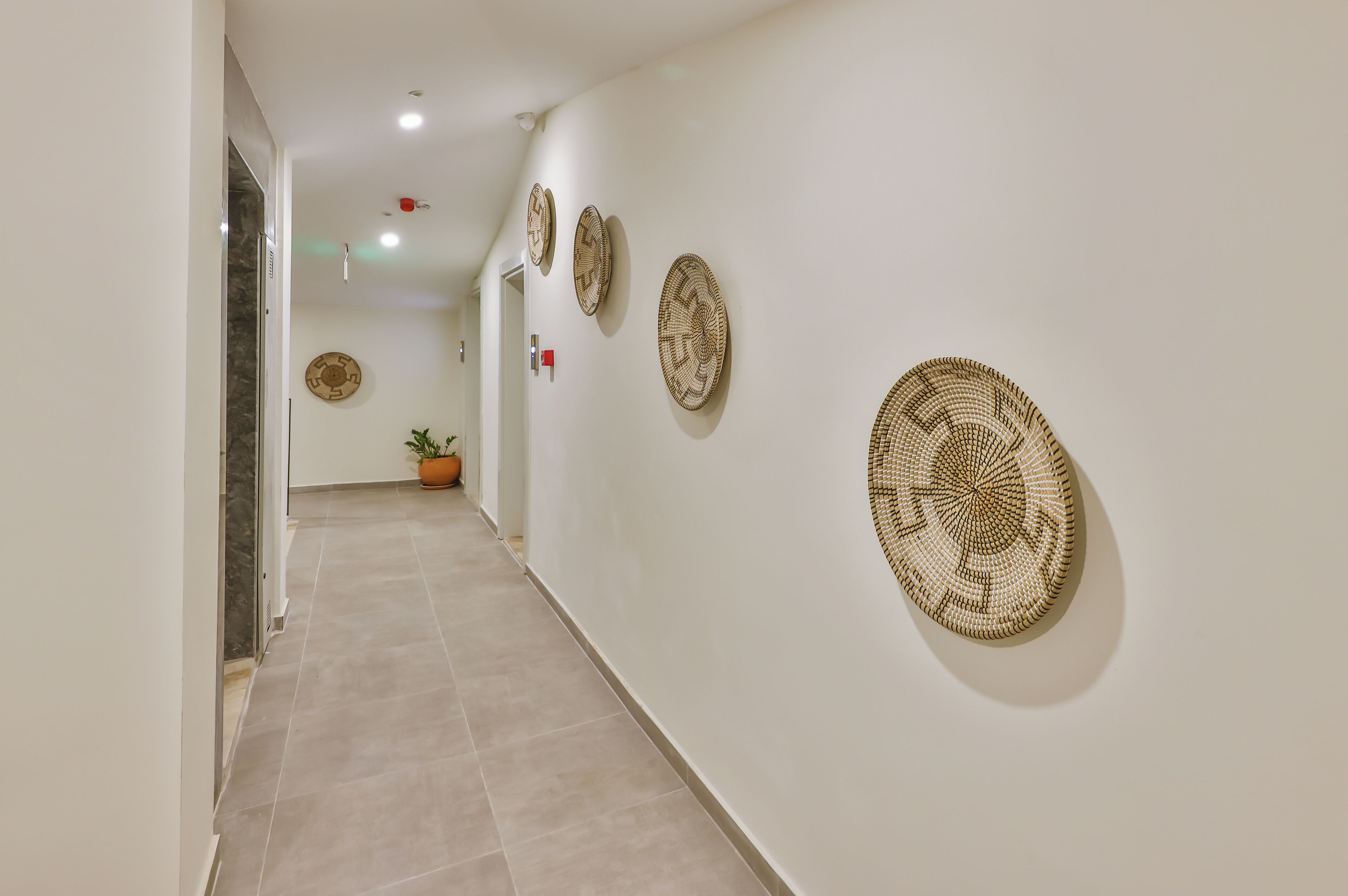 A hallway with a tiled floor and walls adorned with circular woven wall hangings.