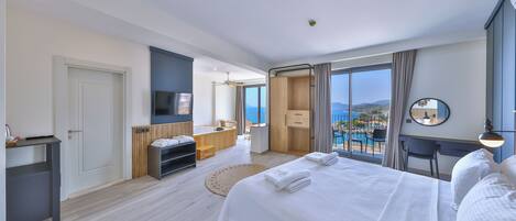 Una habitación de hotel moderna con una cama grande, un escritorio, un televisor y vista al mar.