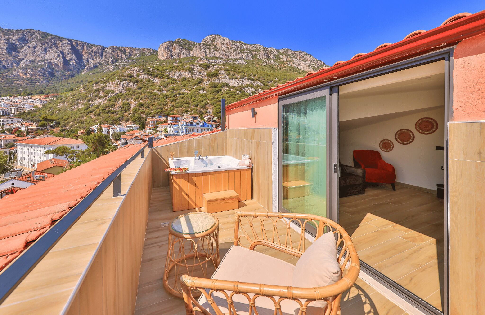 A balcony with a hot tub, wicker furniture, and a view of the town and mountains.