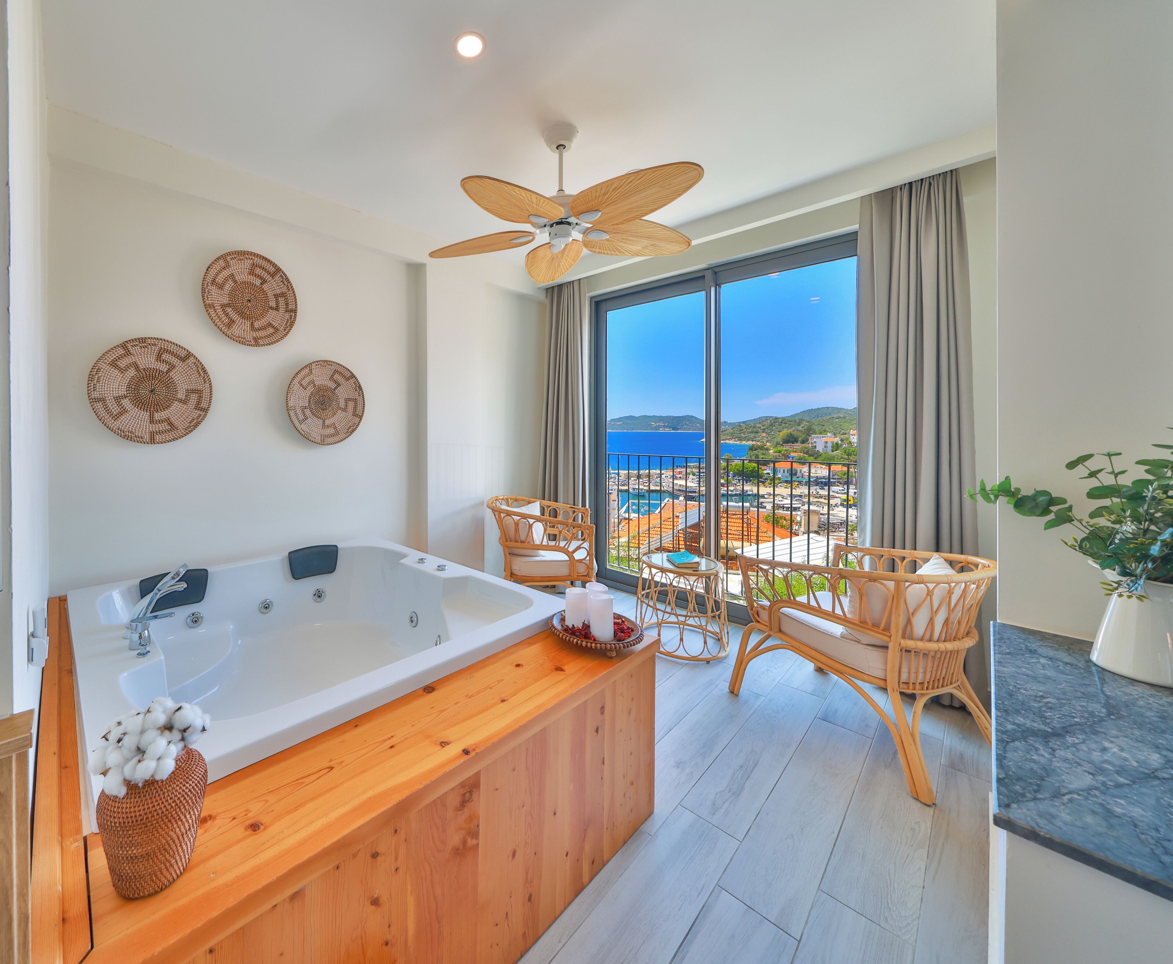 Ein modernes Badezimmer mit einer großen Badewanne, einem Deckenventilator und Meerblick.