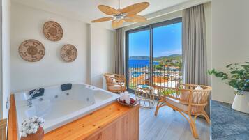 Ein modernes Badezimmer mit einer großen Badewanne, einem Deckenventilator und Meerblick.