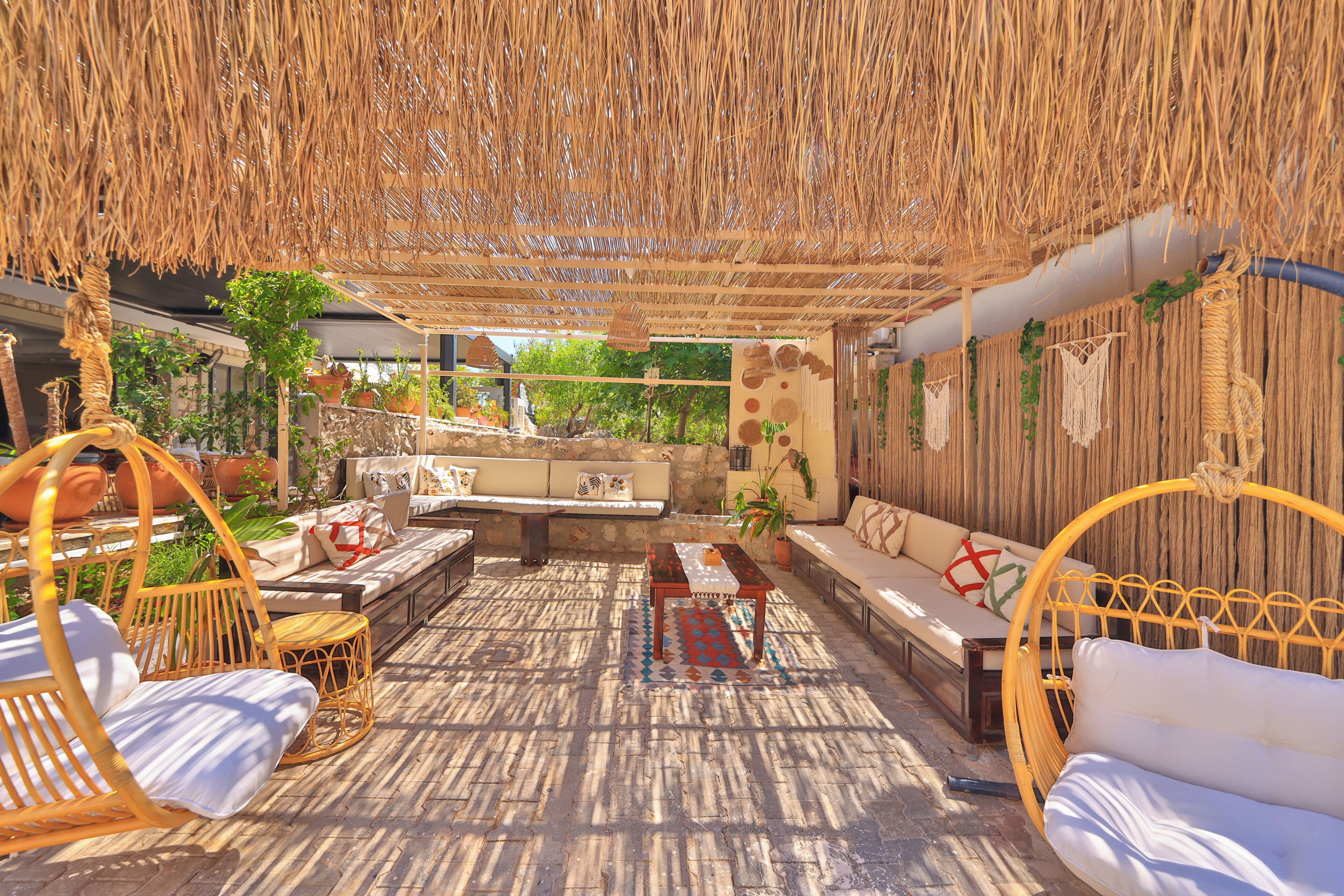 A covered outdoor seating area with wicker furniture, a patterned rug, and a stone wall.